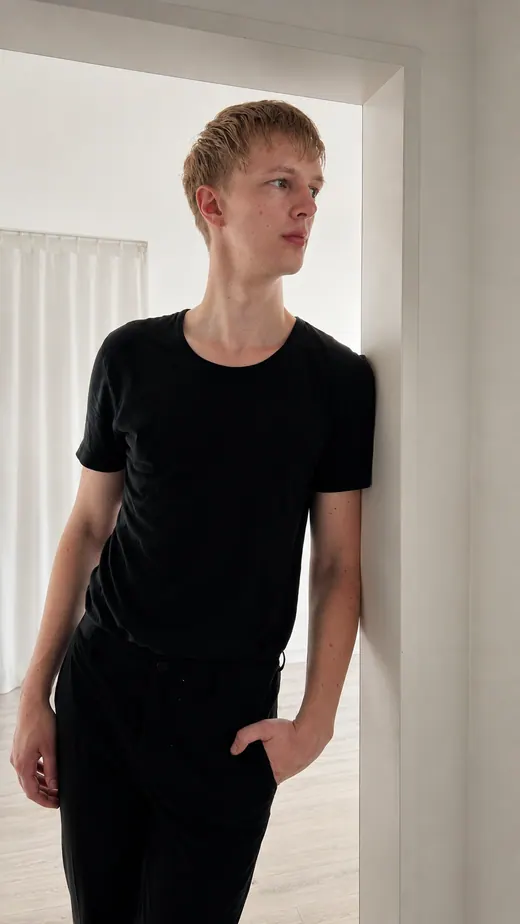Lars Möllering steht in einem hellen Türrahmen, schwarzes Outfit, ruhige architektonische Komposition.