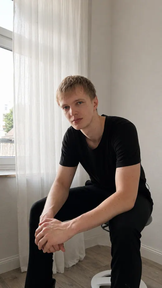 Sitzendes Portrait von Lars Möllering auf einem Stuhl, leicht nach vorne gebeugt, ruhig und reflektiert.